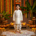 5-year-old boy wearing a white silk shirt set with gold border in a South Indian festive setting